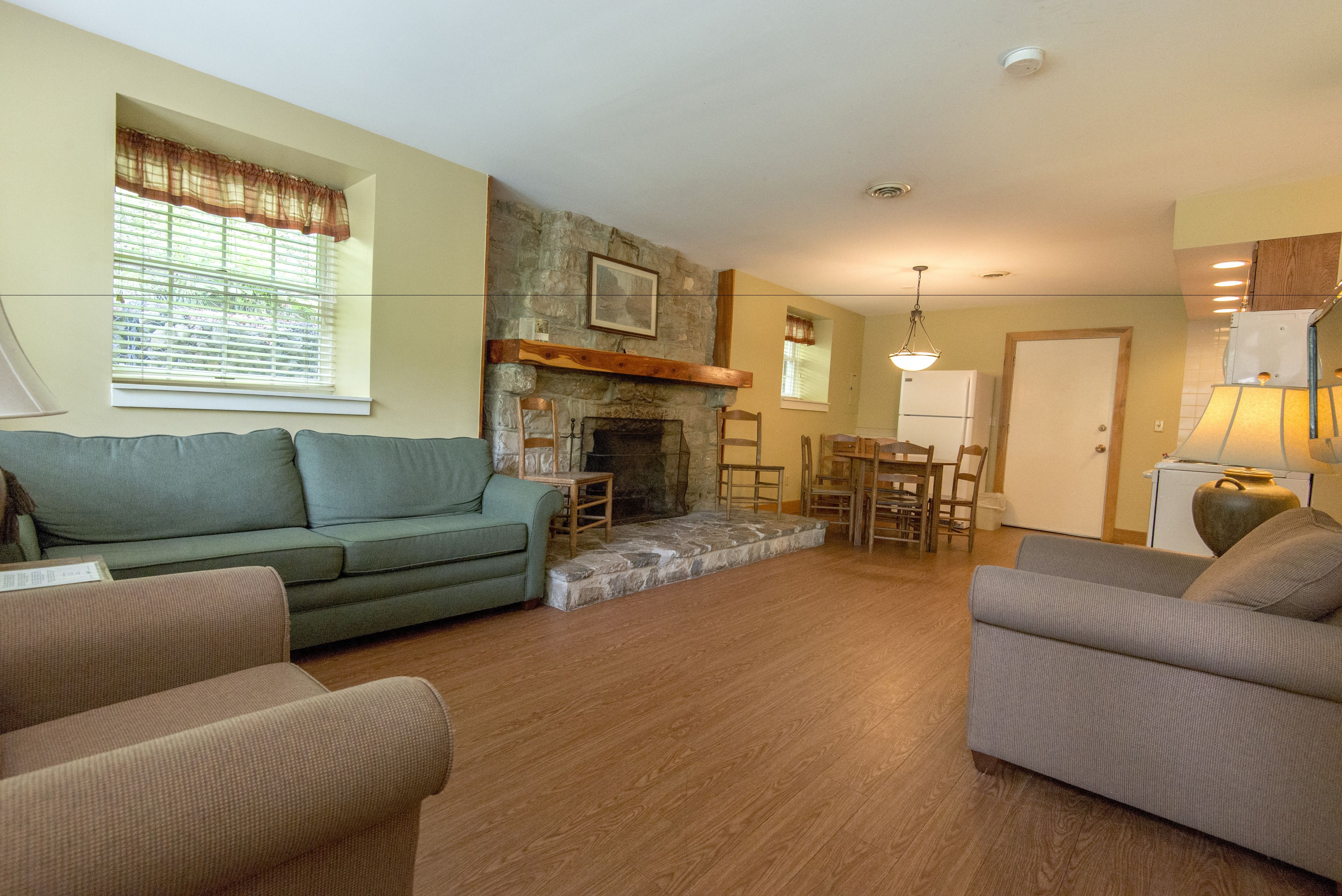 A living room with a fireplace, a sofa, a dining table with chairs, and a lamp.
