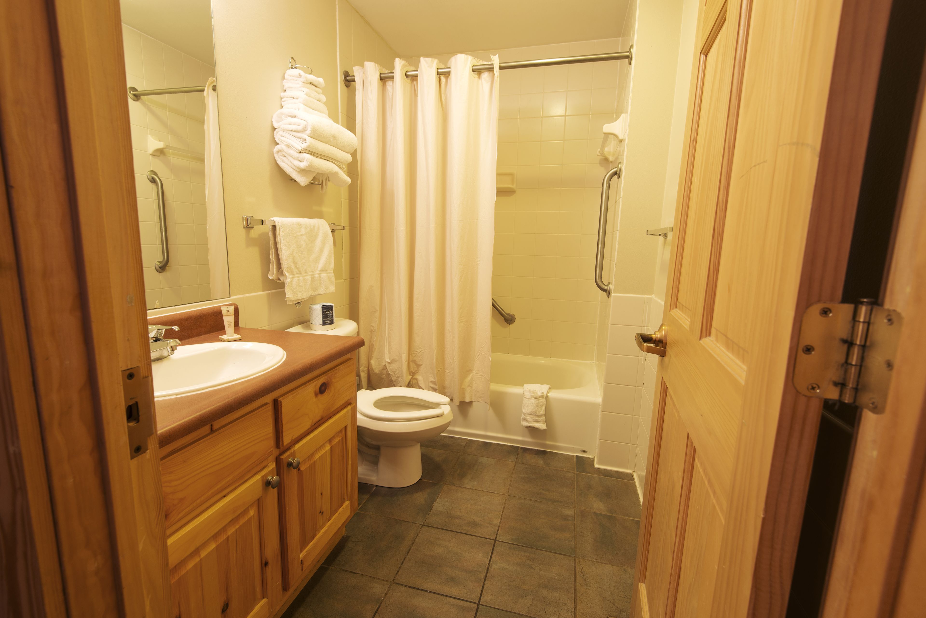 A bathroom with a wooden vanity, a toilet, a bathtub, and a shower.