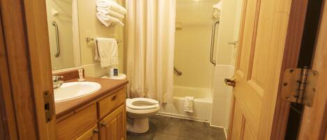 A bathroom with a wooden vanity, a toilet, a bathtub, and a shower.