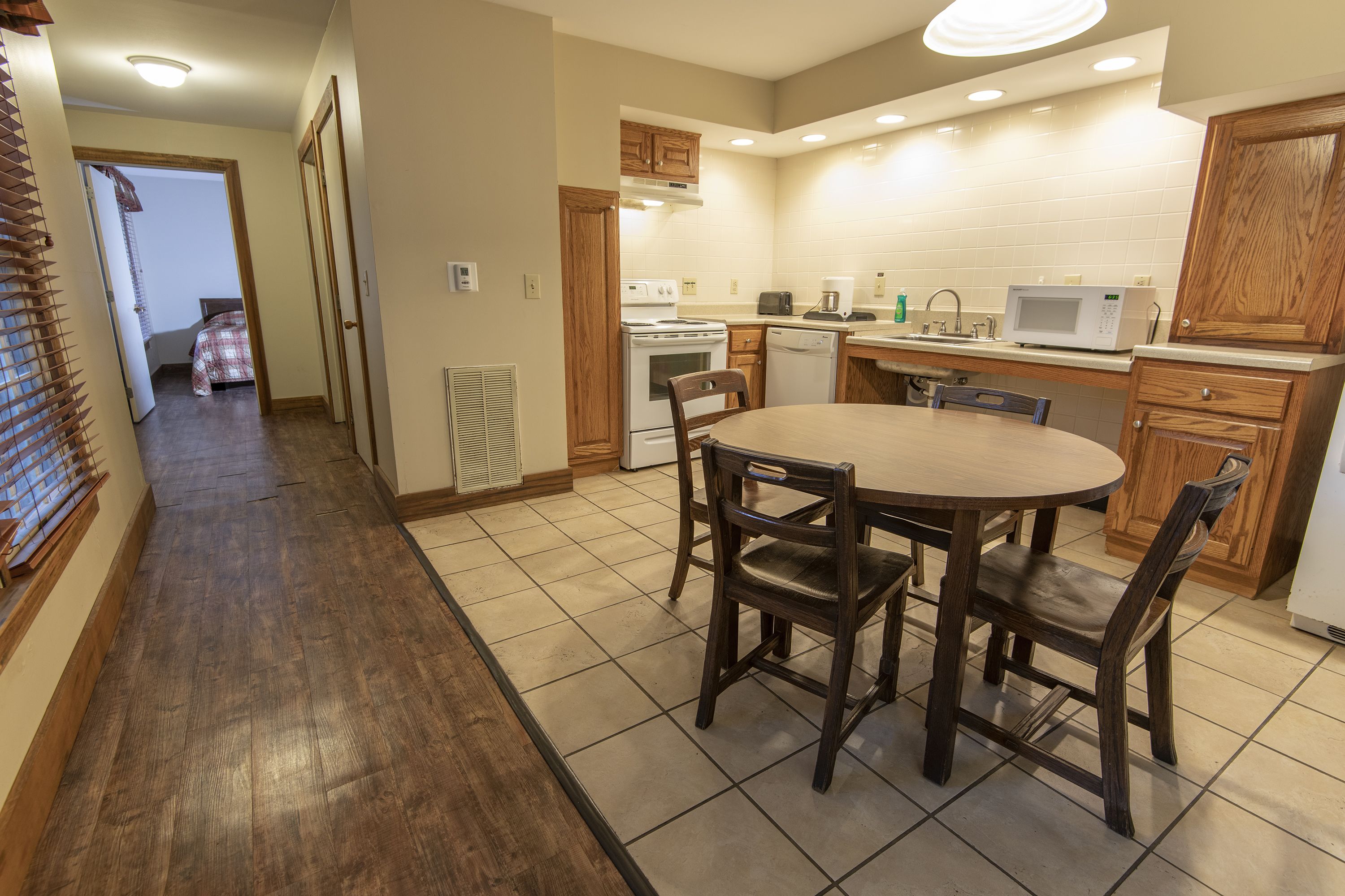 A kitchen with wooden cabinets, a microwave, a stove, and a dining table with chairs.