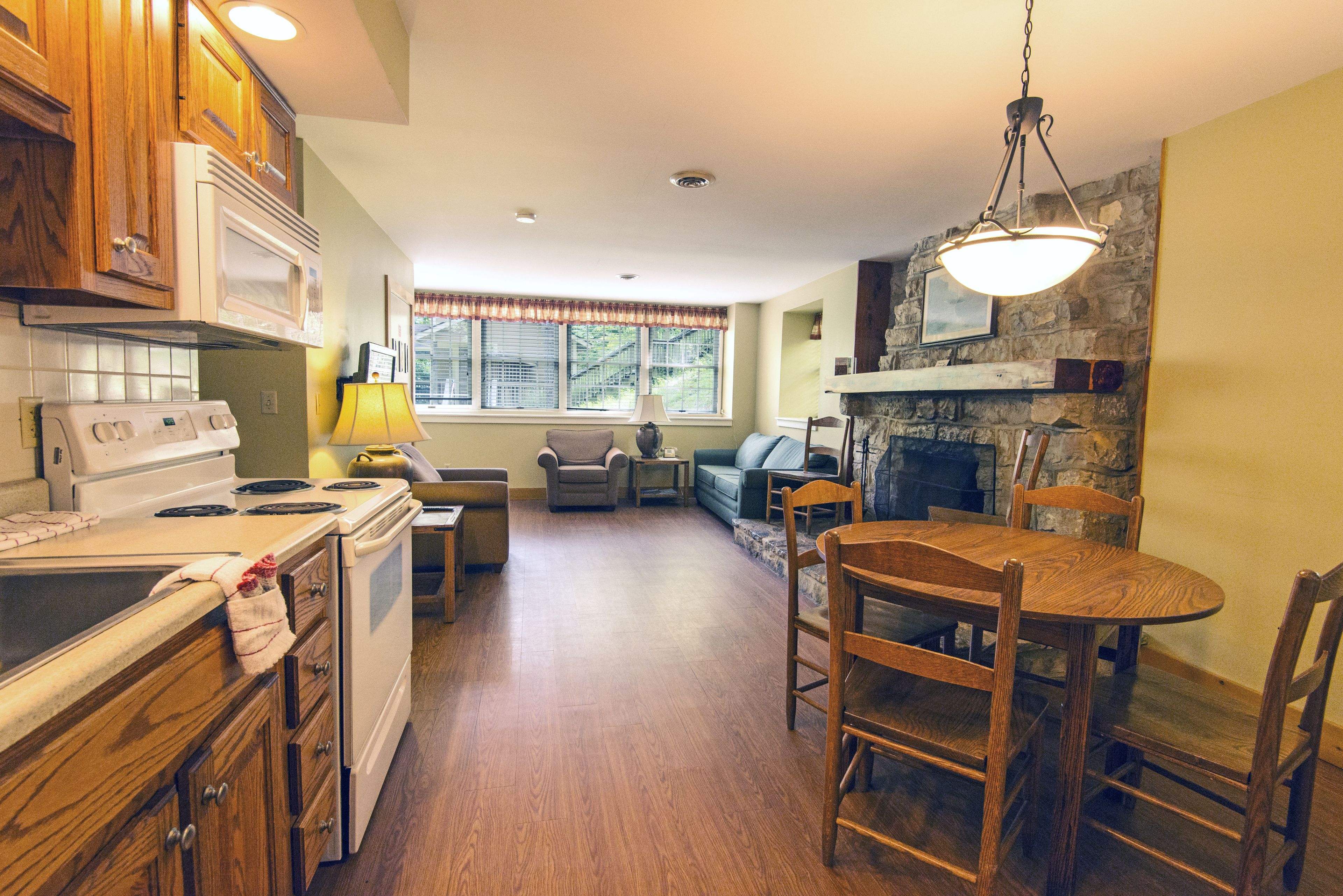 A kitchen with wooden cabinets, a stove, and a dining area with a table and chairs.