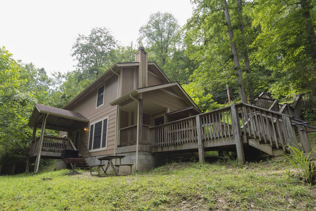 A two-story cabin with a porch and a staircase leading to a deck.