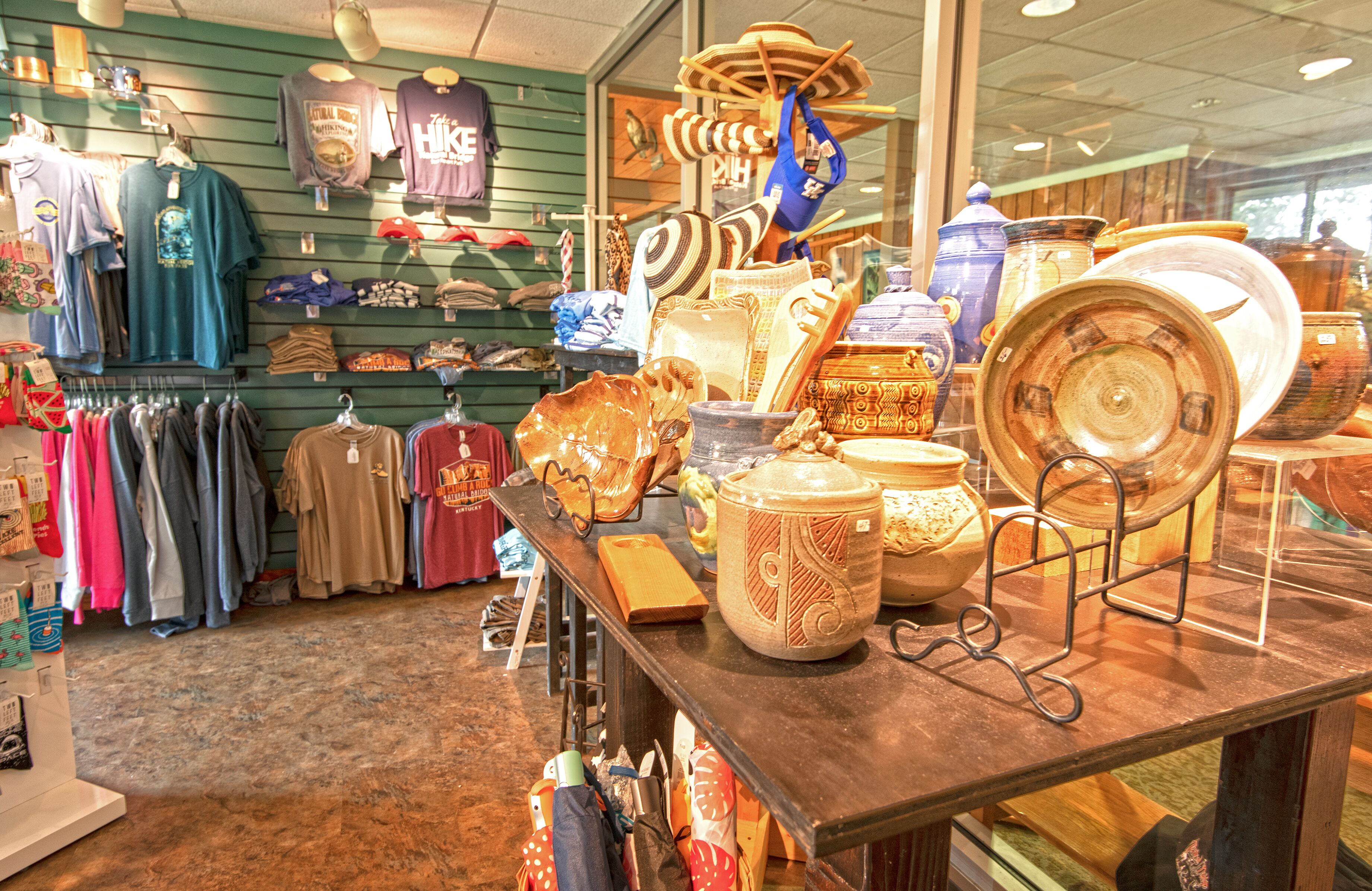 A retail store with shelves of clothing and a display of pottery and ceramics.