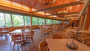 A spacious dining area with wooden tables and chairs, large windows offering a view of the outdoors, and a high ceiling with chandeliers. - Natural Bridge State Resort Park (Slade)