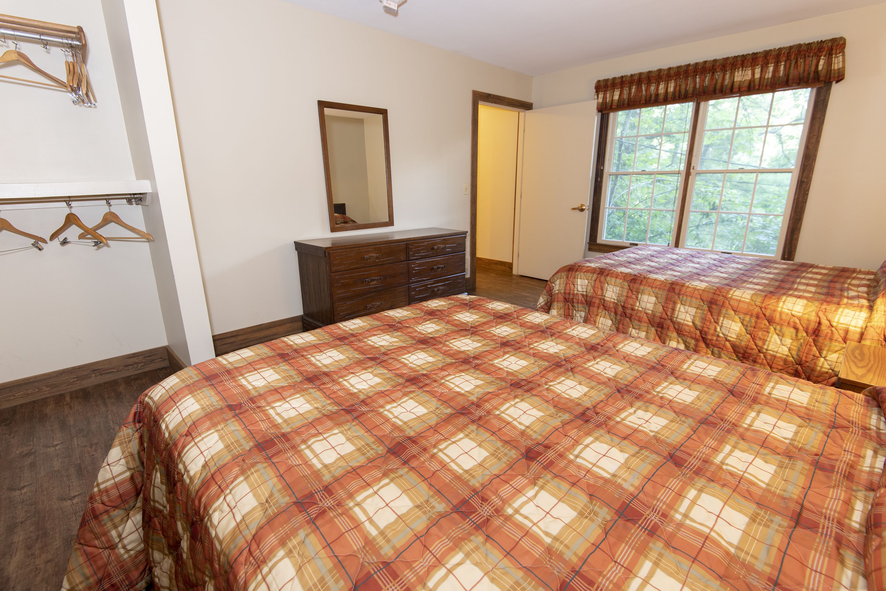 Un dormitorio con dos camas, un aparador, un espejo y una ventana con cortinas.
