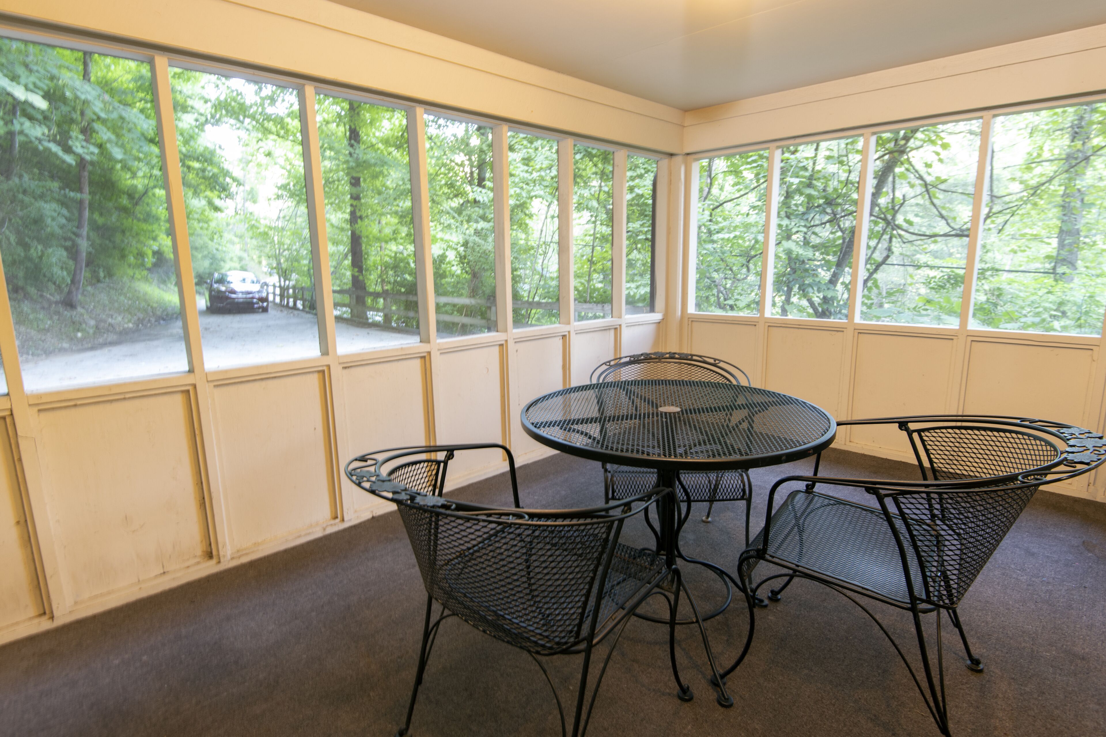 A room with a large window, a round table, and four chairs.