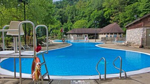 A swimming pool with a lifeguard stand, a no diving sign, and a covered area with lounge chairs. - Natural Bridge State Resort Park (Slade)