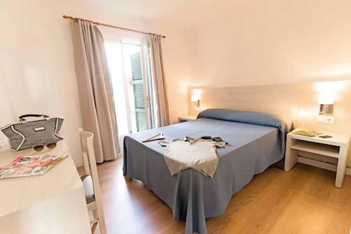 A bedroom with a bed, bedside tables, a desk, and a chair.