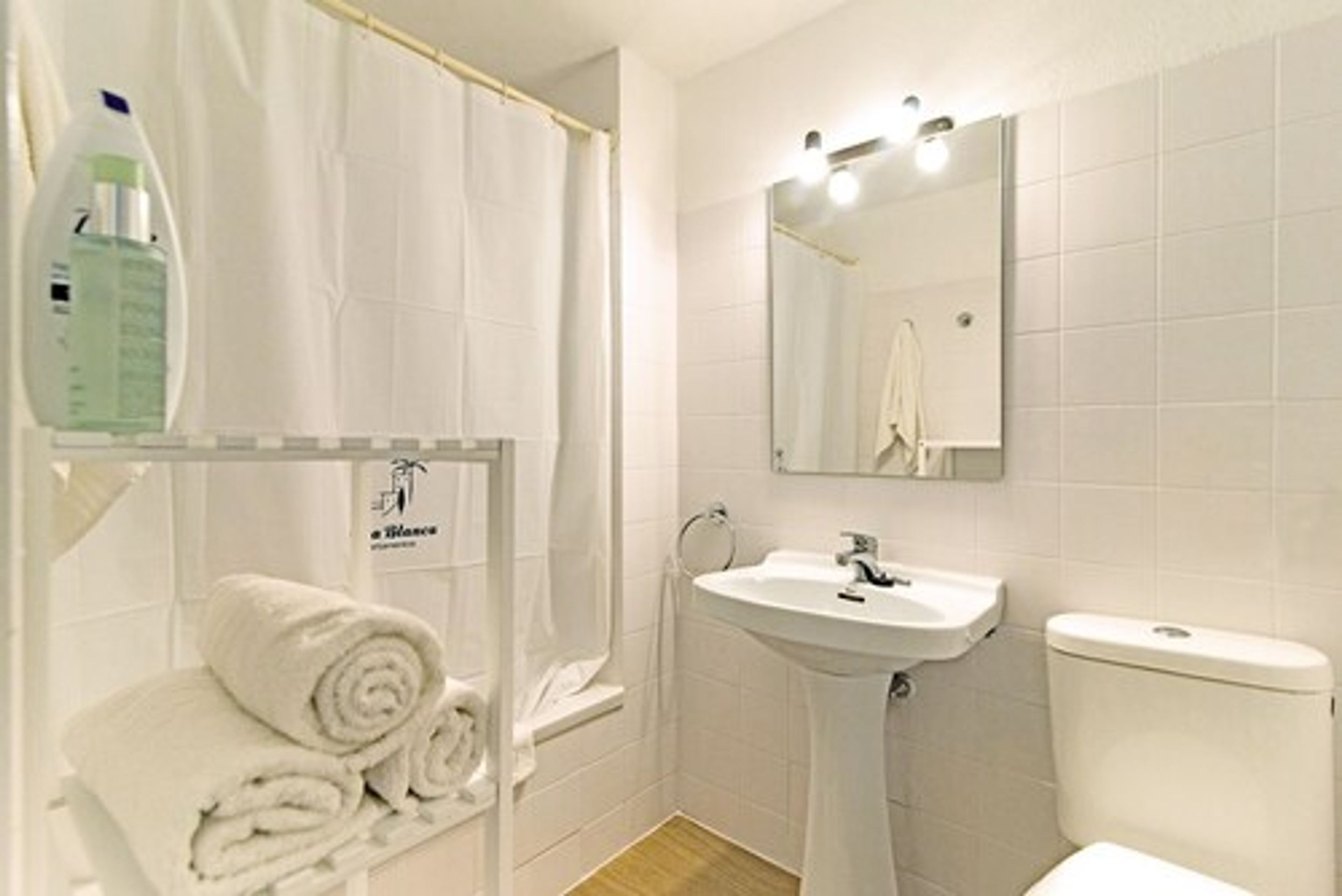 A bathroom with a shower, sink, toilet, and a towel rack with towels.
