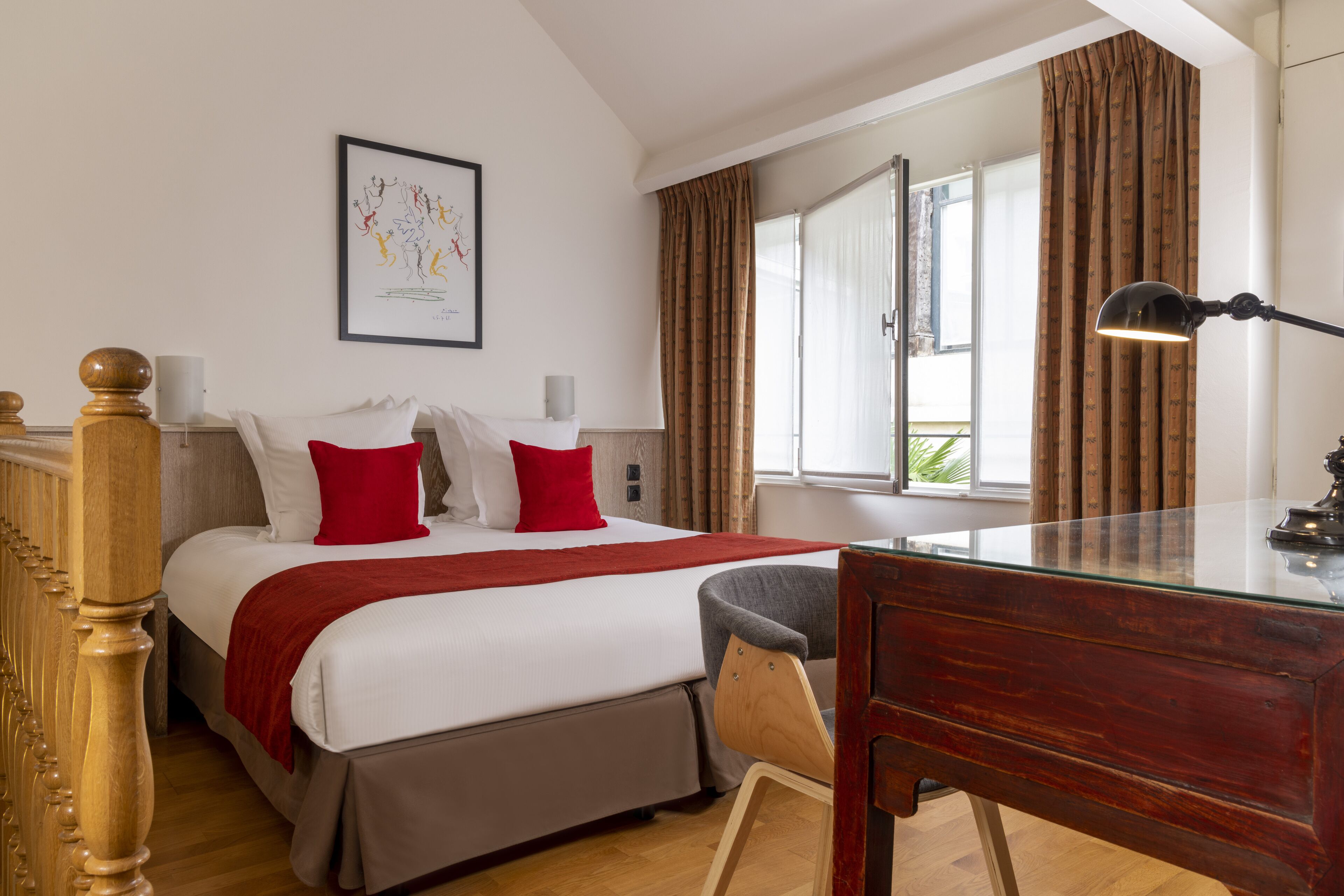 A bedroom with a bed, a desk, a chair, a lamp, and a window with curtains.