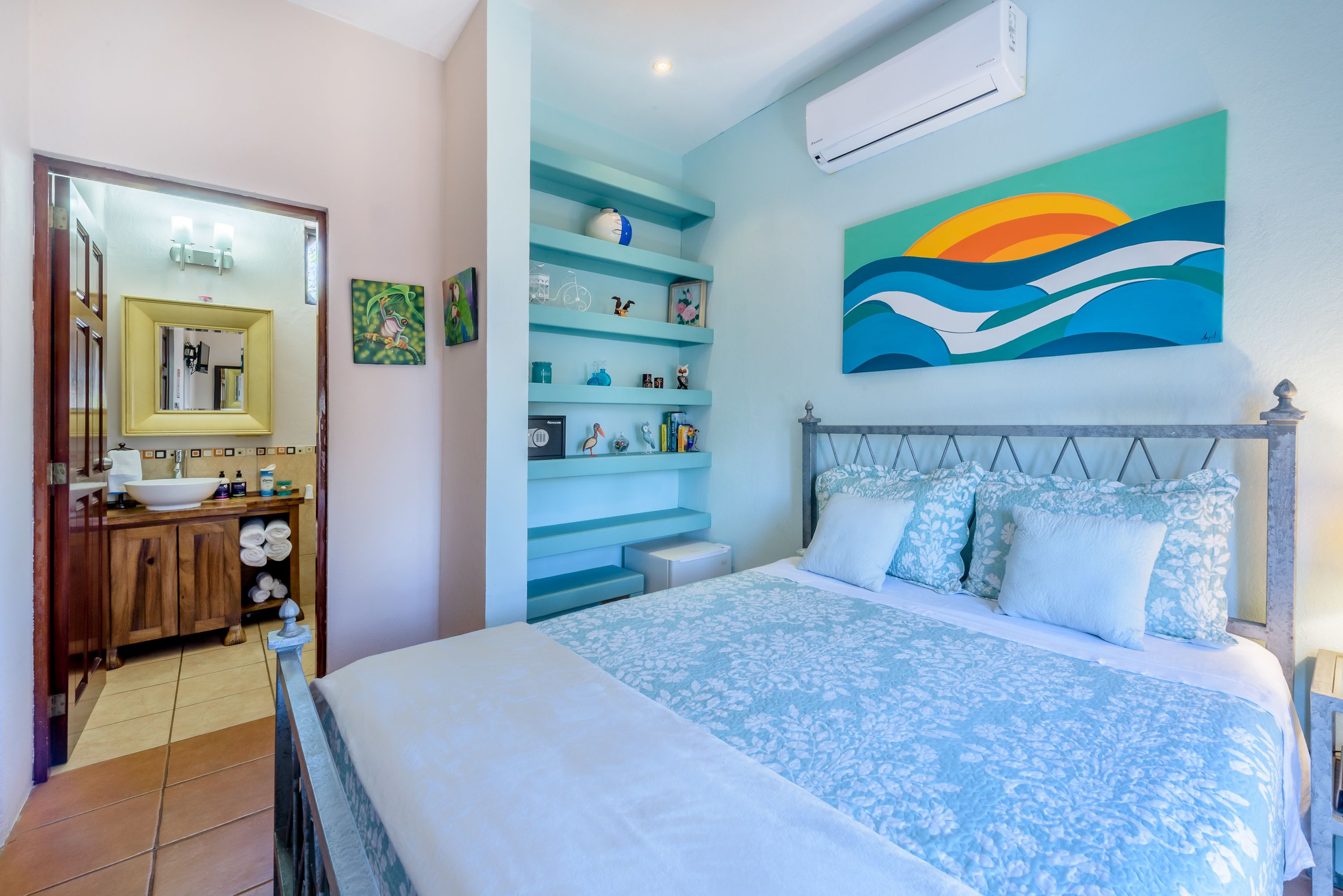 Une chambre à coucher comprenant un lit, une table de chevet, une commode, un miroir et une étagère avec des objets décoratifs.