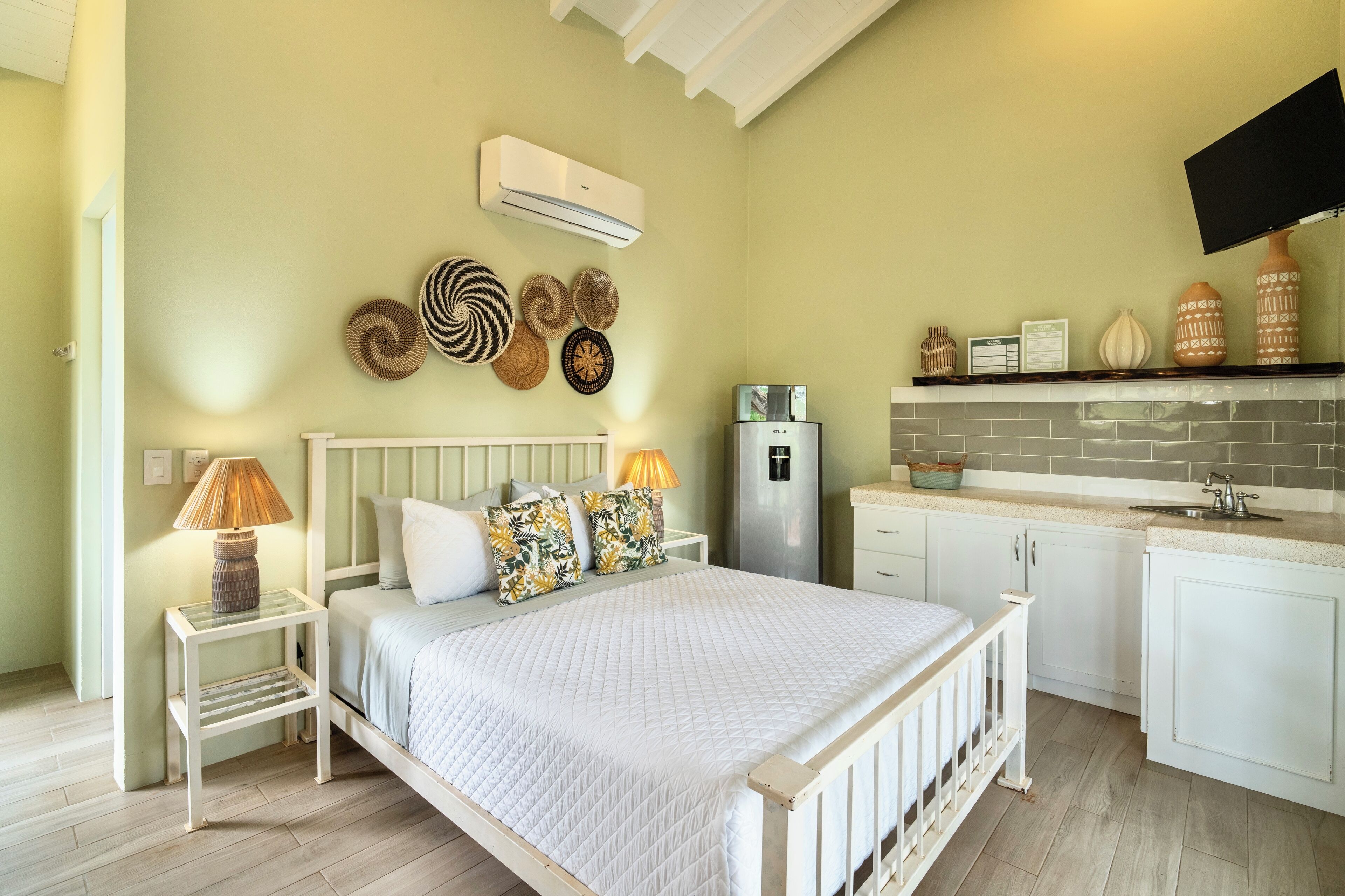 A bedroom with a bed, bedside tables, a lamp, and a wall-mounted air conditioner.