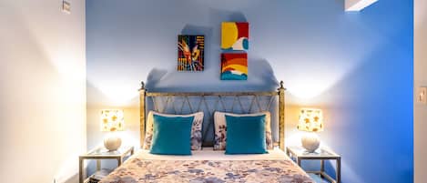 Ein Schlafzimmer mit einem Bett, zwei Nachttischen, zwei Lampen und einem Deckenventilator.