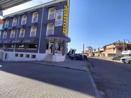 Un hotel con restaurante en la planta baja, que presenta una fachada curva y una escalera que conduce a la entrada.