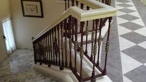 A marble staircase with a white handrail and dark balusters, leading to a landing with a framed picture. - Hotel Pozo De La Nieve (Tordesillas)