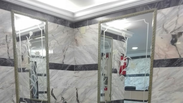 A corner room with a dark leather sofa, a small table, and marble walls with two large mirrors. - Hotel Pozo De La Nieve (Tordesillas)