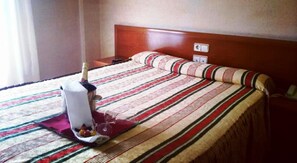 Une chambre d’hôtel avec un lit, une table de chevet, une bouteille et une télécommande.