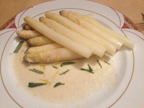 Um prato de aspargos com molho cremoso e finalizado com ervas.