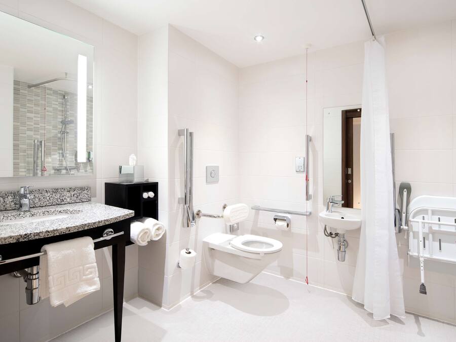 A modern bathroom with a granite countertop sink, a toilet, a shower area, and a separate sink.