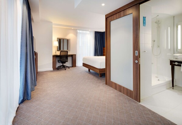 A hotel room with a bed, desk, chair, and a shower area. - Hampton by Hilton Dundee City Centre (Dundee)