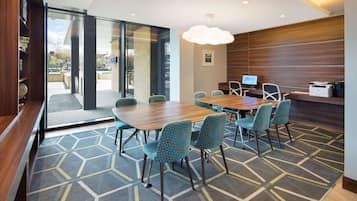 Una sala de reuniones moderna con una mesa grande, alfombra estampada y sillas color turquesa.