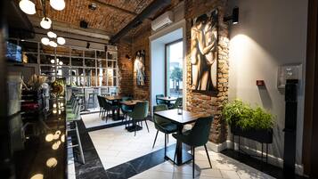 A modern restaurant with brick walls, green chairs, and a black marble floor.