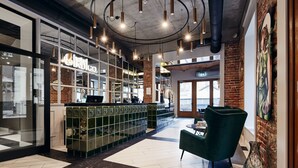 Un hall d’hôtel avec un bar, des sièges verts et une grande fenêtre.