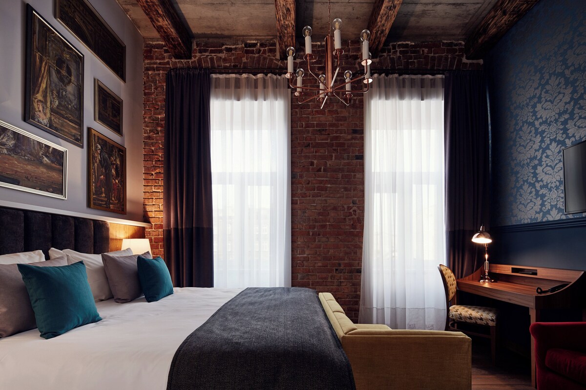 Une chambre d’hôtel avec un grand lit, un bureau, une chaise et un téléviseur fixé au mur.