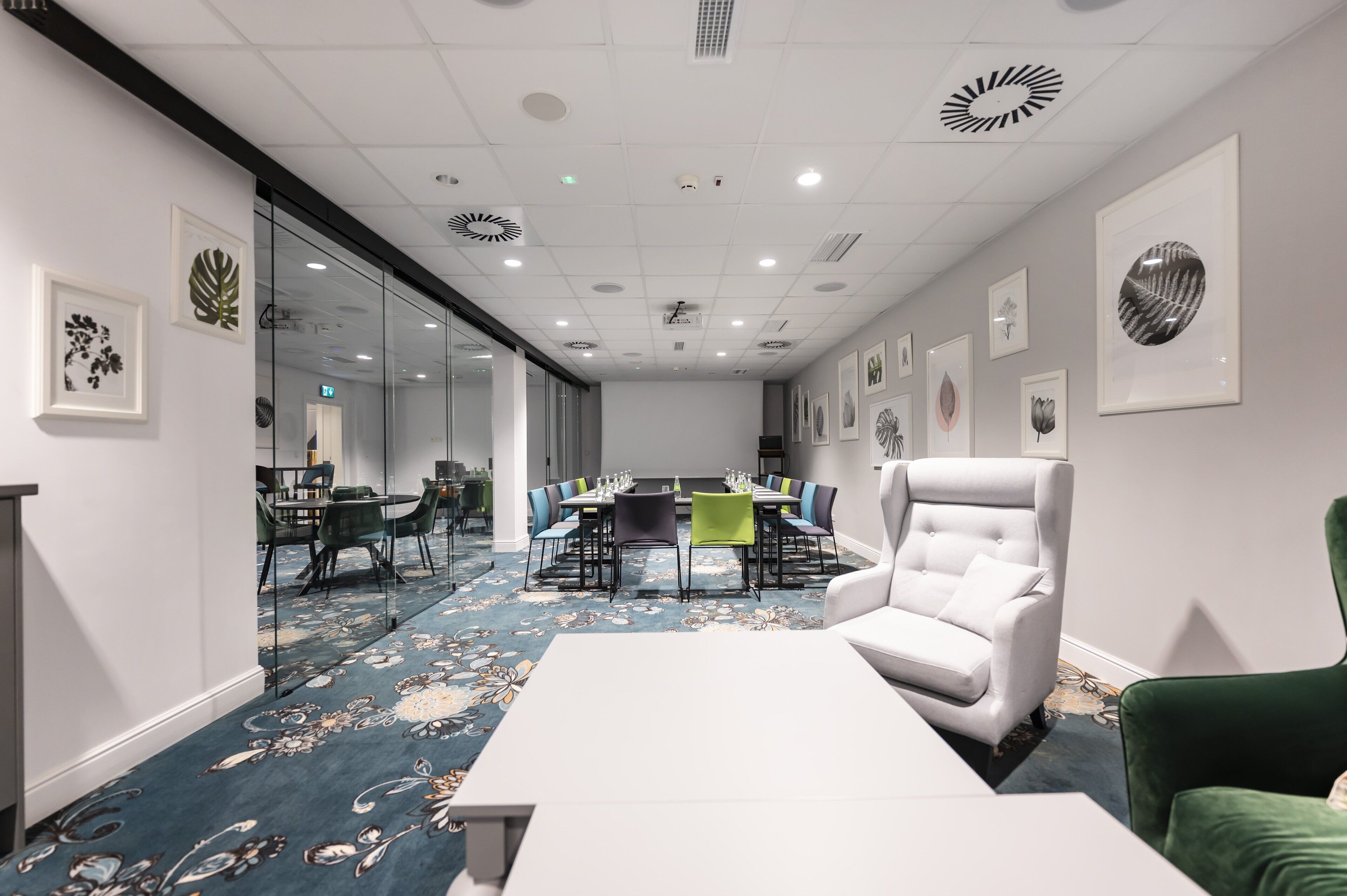 A conference room with a long table, chairs, and a white armchair.