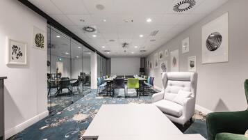 A conference room with a long table, chairs, and a white armchair.
