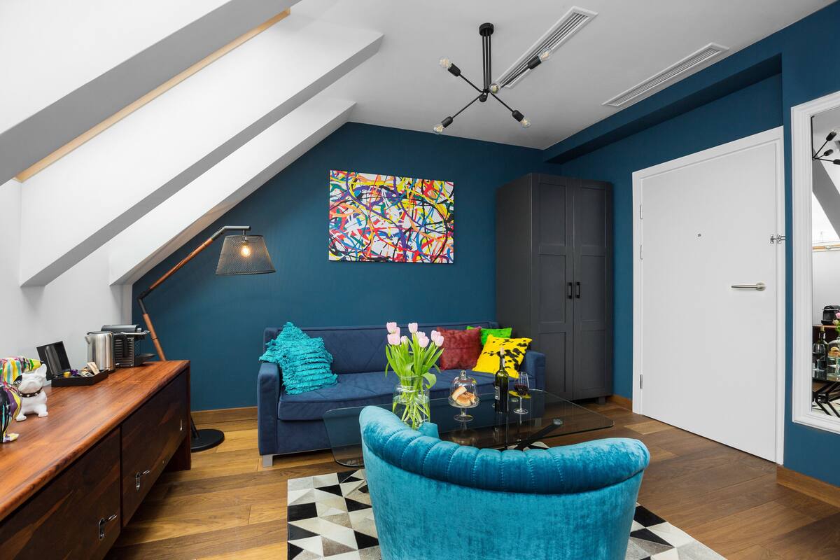 Ein modernes Wohnzimmer mit einem blauen Sofa, einem Glastisch und einer Holzkommode.