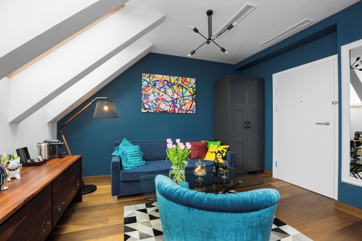 Un salon moderne avec un canapé bleu, une table basse en verre et un buffet en bois.