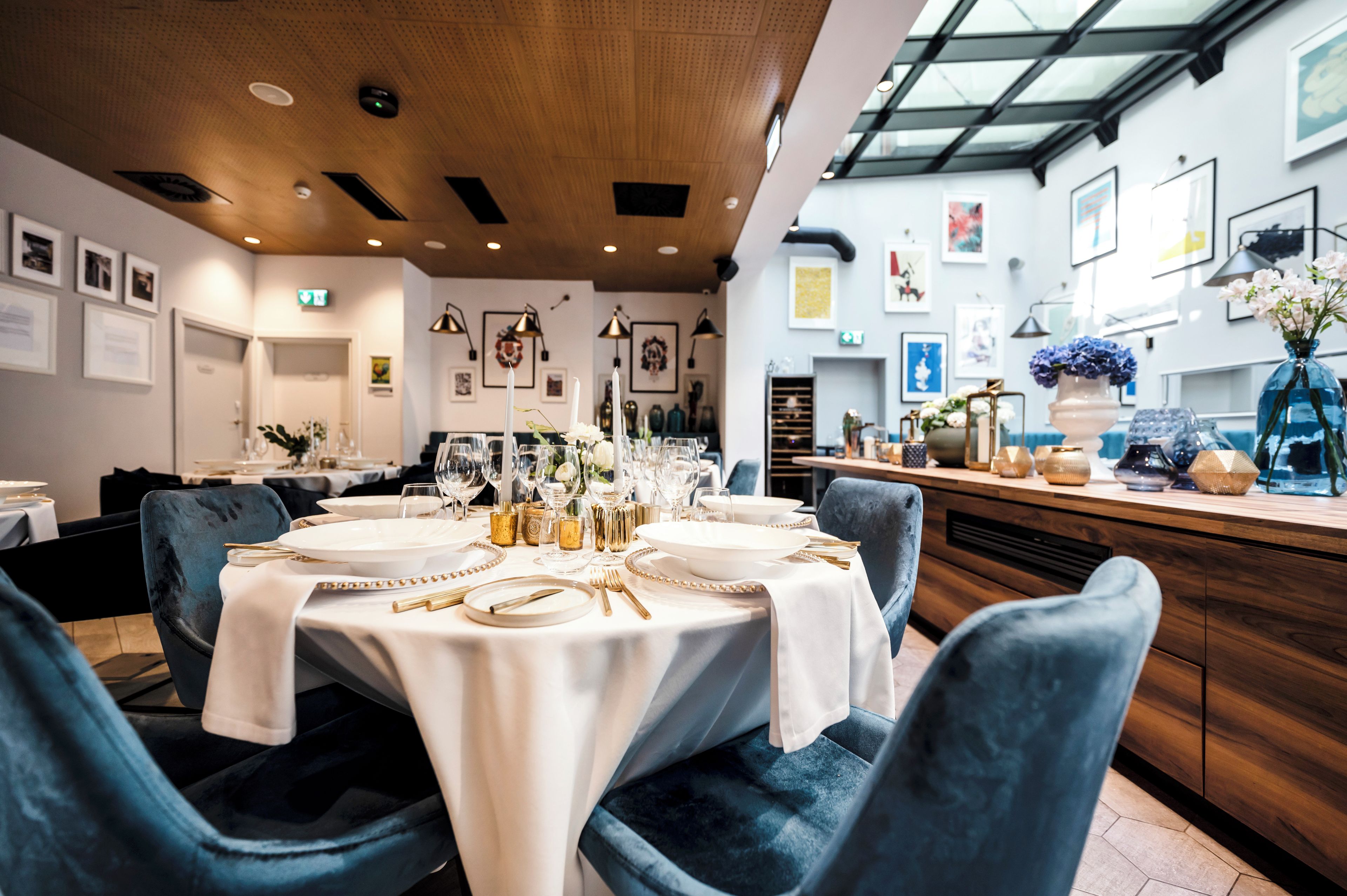 Ein Restaurant mit runden Tischen, gedeckt für ein Essen, mit weißen Tischdecken und goldenen Akzenten.