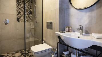Une salle de bain moderne avec une douche à parois de verre, des toilettes blanches, un lavabo avec un miroir et un porte-serviettes.