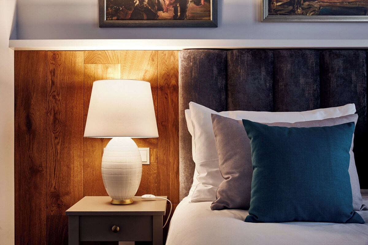 Un lit bien fait, avec un oreiller blanc et turquoise, une lampe de chevet et une tête de lit en bois.
