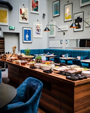 Un restaurant moderne doté d’un îlot central où sont présentés divers plats, et d’une banquette bleue en tissu à l’arrière-plan.