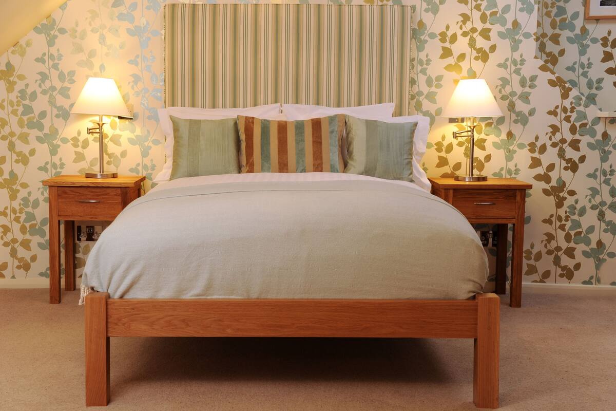 A bedroom with a bed, two nightstands, and two lamps.