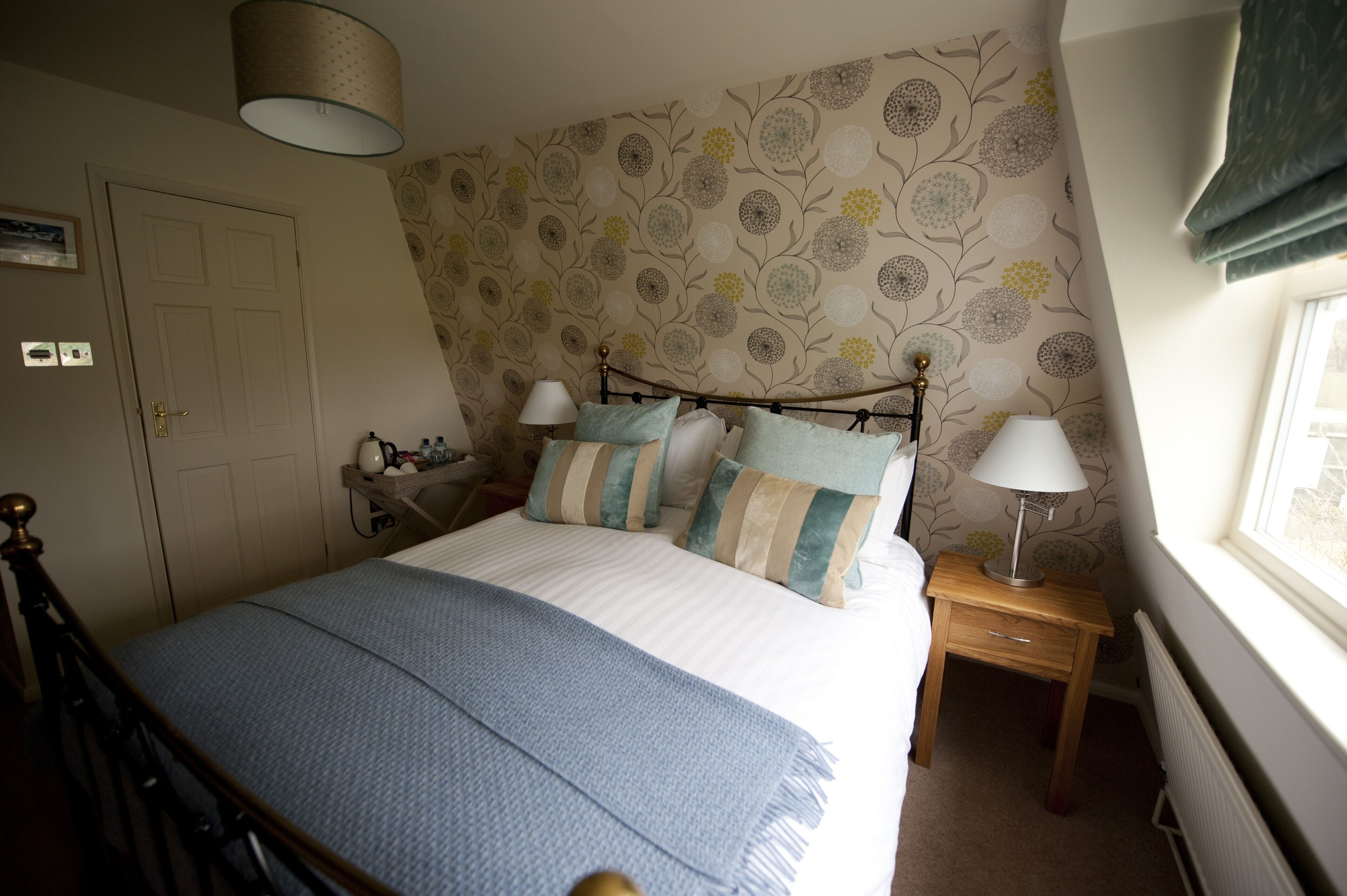 A bedroom with a bed, bedside tables, lamps, a door, and a window.