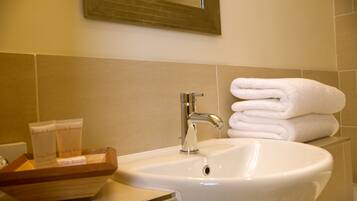 A bathroom with a sink, a mirror, and a stack of white towels.