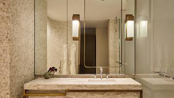 A modern bathroom with a marble sink, a large mirror, and two wall-mounted lights.