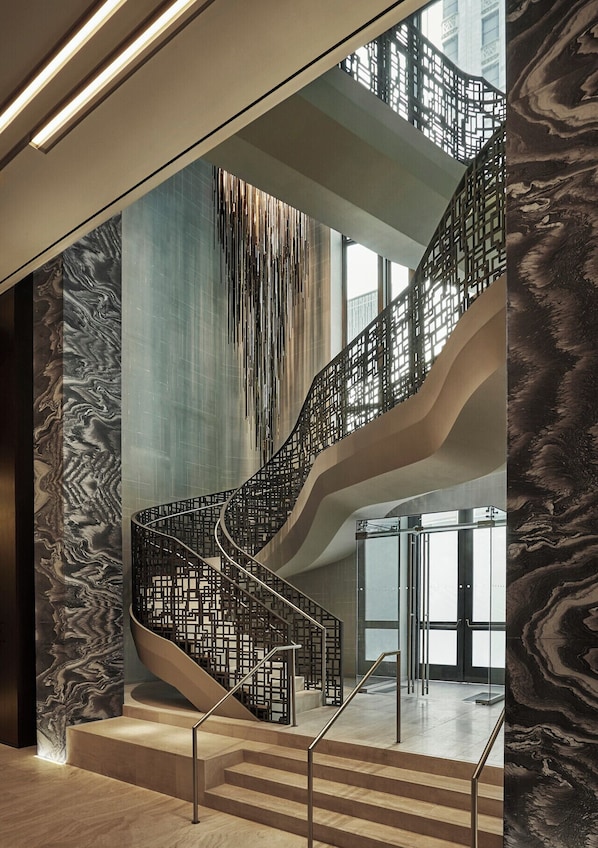 A modern spiral staircase with a metal railing, leading to an upper level.