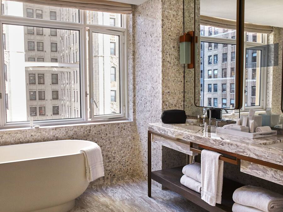 Ein Badezimmer mit einer Badewanne, einem Waschtisch mit Spiegel und Handtüchern.