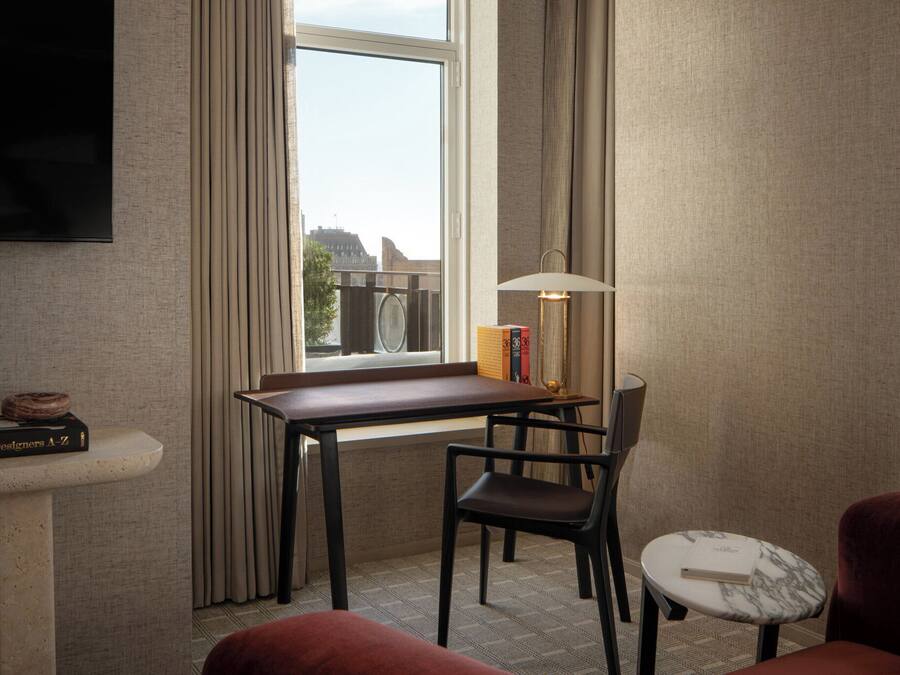 Ein Hotelzimmer mit Schreibtisch, Stuhl und einem an der Wand montierten Fernseher.