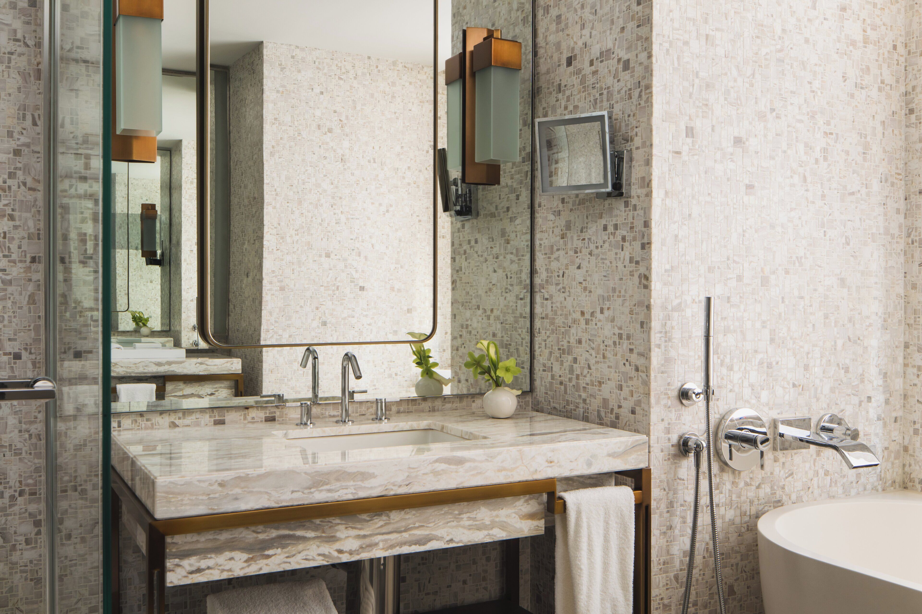 A modern bathroom with a marble sink, a large mirror, and a shower area.