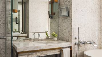 A modern bathroom with a marble sink, a large mirror, and a shower area.