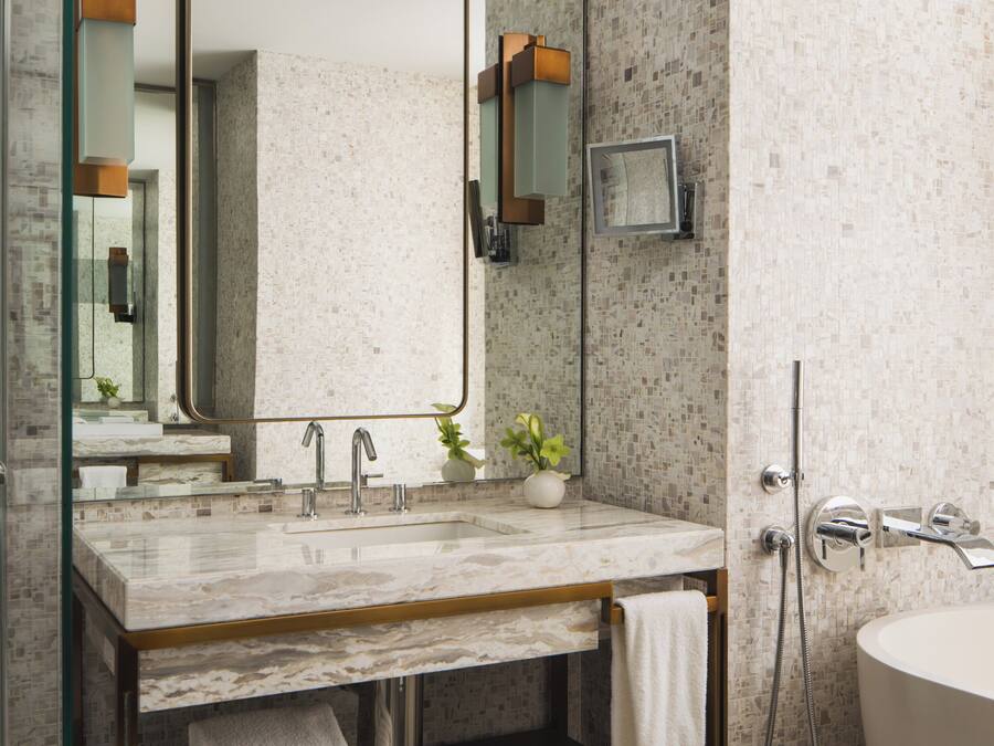 A modern bathroom with a marble sink, a large mirror, and a shower area.