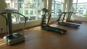 Ein Fitnessraum mit Laufbändern und einem Ergometer, großen Fenstern und Holzboden.