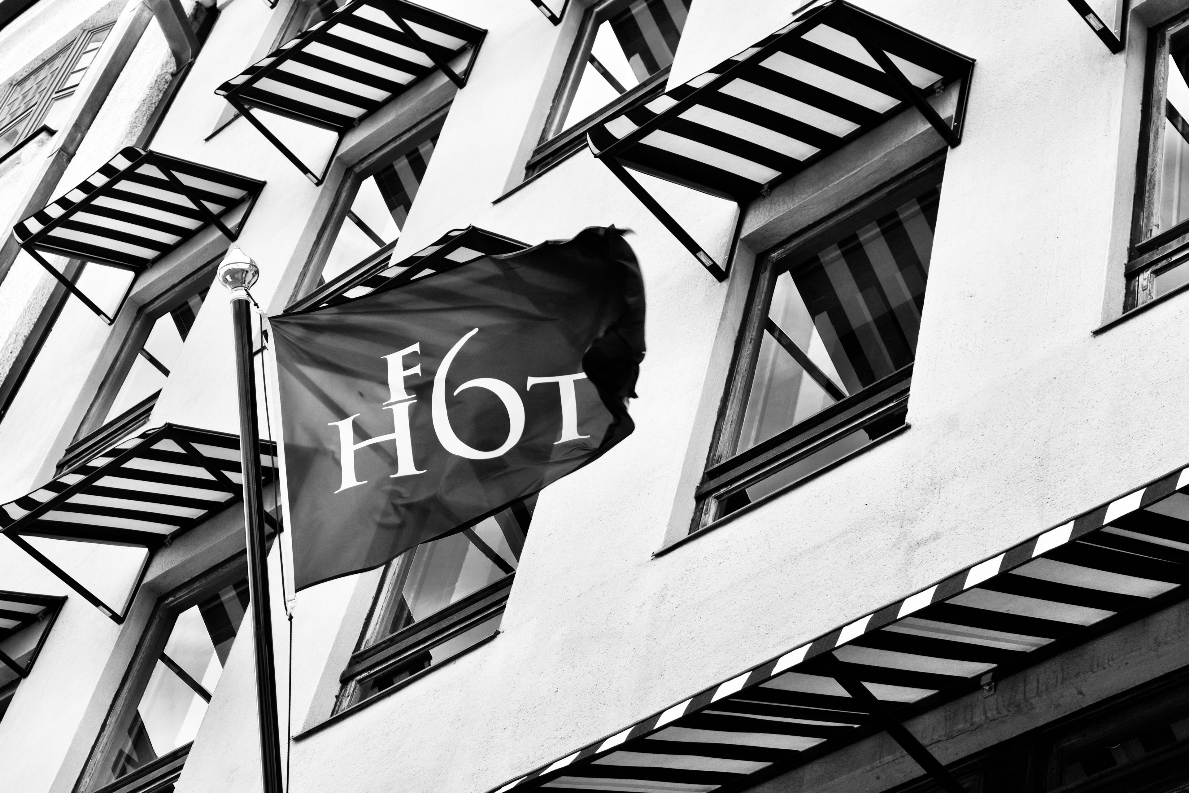 A building with multiple windows and a flag with the letters "HOT" on a pole.