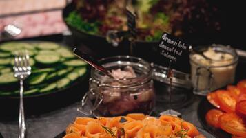 A buffet with various dishes including salmon, salad, and sliced vegetables.