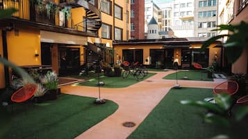 A courtyard with a spiral staircase, outdoor seating, and greenery.